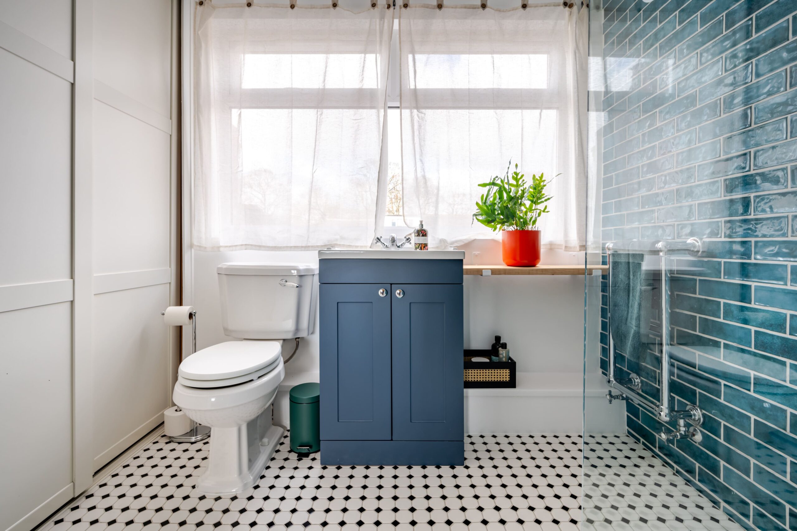 Modern bathroom with a blue vanity unit, white toilet, black and white floor tiles, and blue subway wall tiles