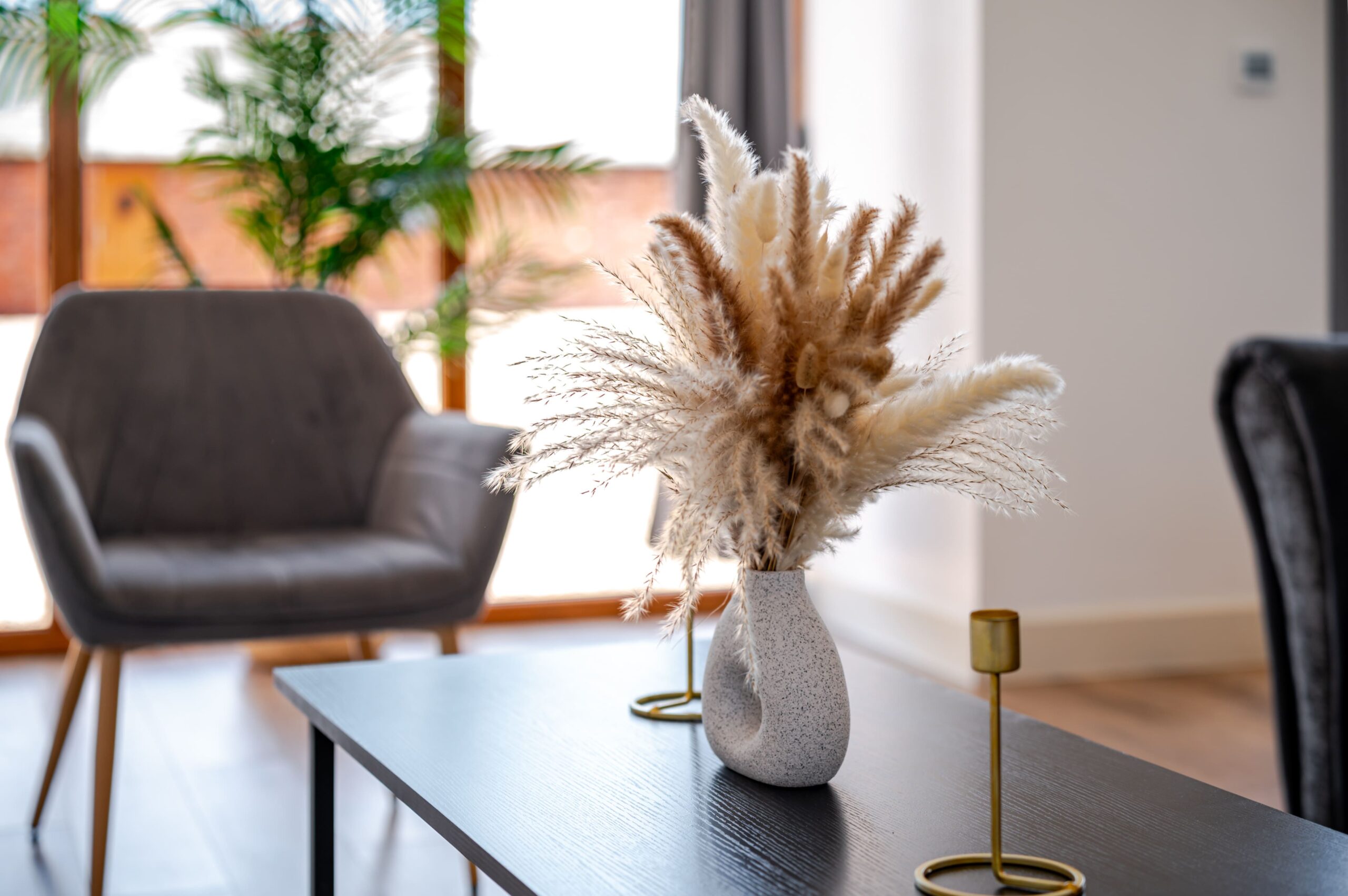 Dried pampas grass in a grey speckled vase on a black coffee table in a modern living room