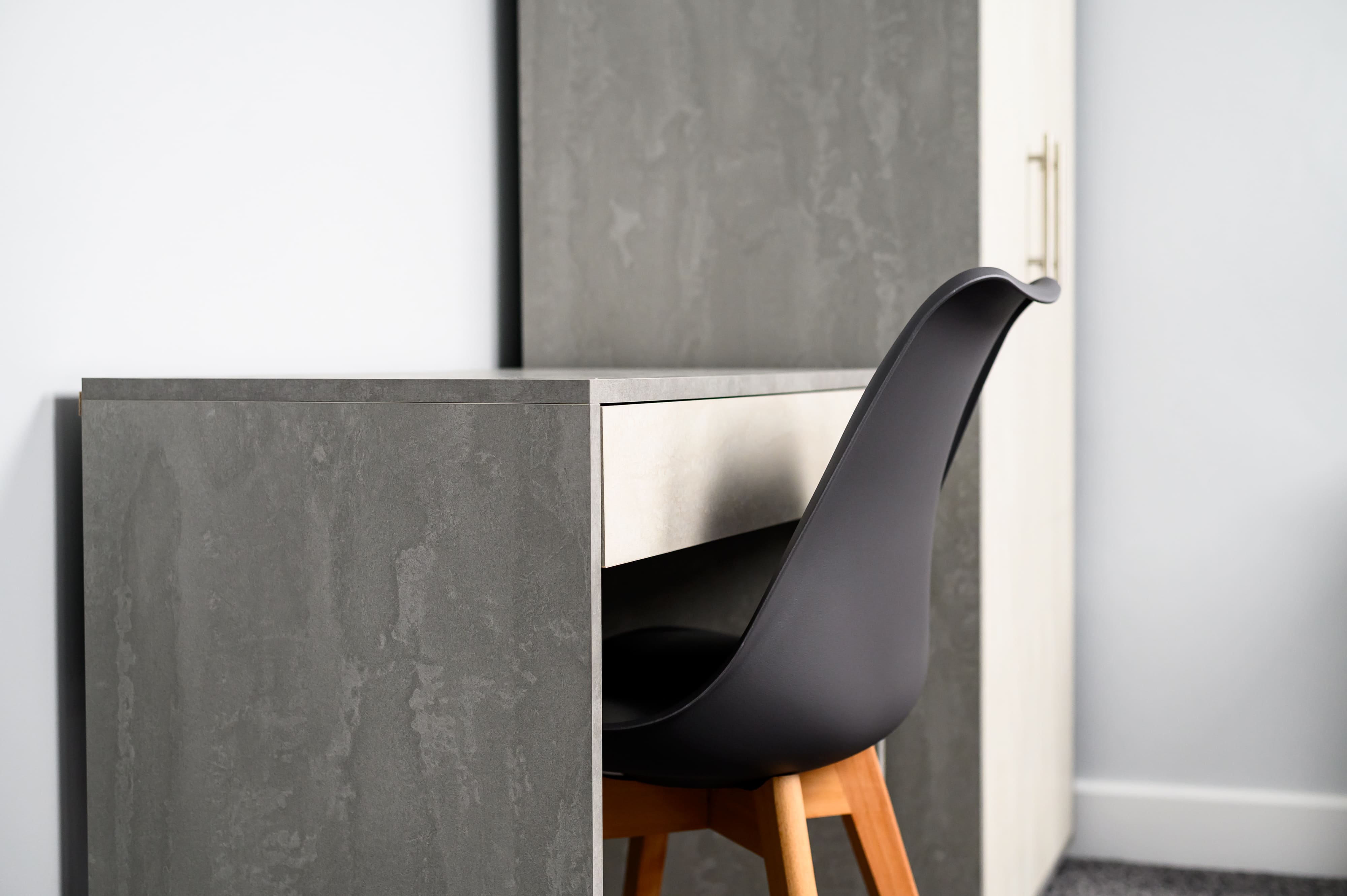 Modern grey stone-effect desk and black chair with wooden legs